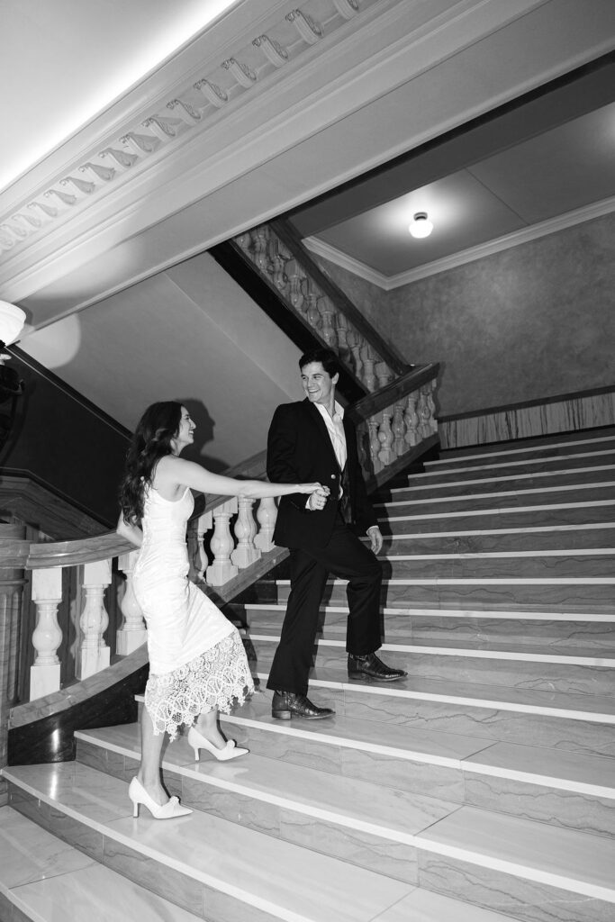 Downtown Dallas engagement shoot in the original City Hall that is now University of Dallas College of Law. Grand Marble stairs. She is in her mom's lace wedding dress. He is in a suit.